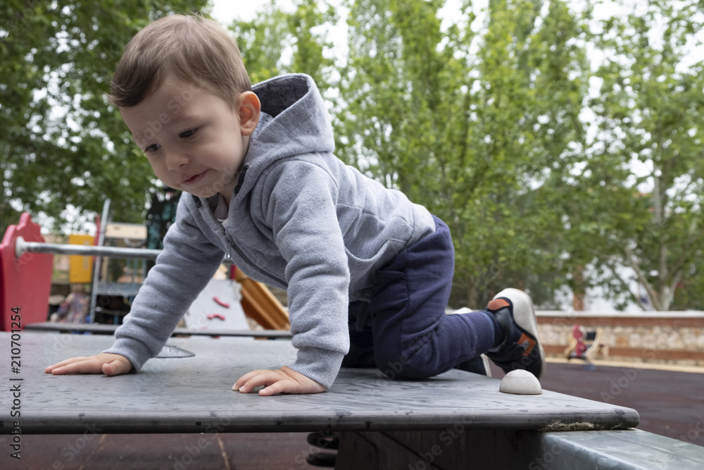 Fototapeta premium Child under two years playing in the park with a gray jacket and blue pants.