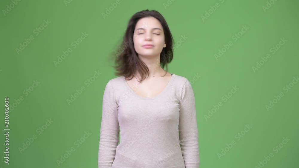 Young beautiful woman nodding no against green background Young beautiful woman nodding no against green background