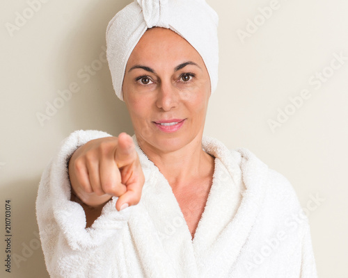 Beautiful middle age woman, wet hair wearing a towel pointing with finger to the camera and to you, hand sign, positive and confident gesture from the front