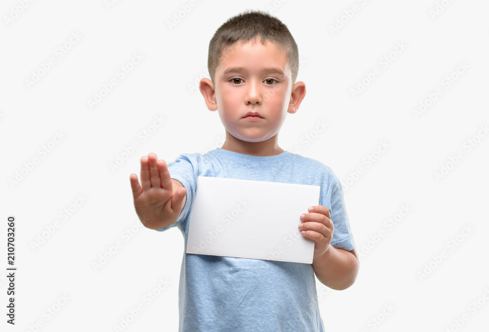 Dark haired little child holding a blank card with open hand doing stop sign with serious and confident expression, defense gesture Dark haired little child holding a blank card with open hand doing stop sign with serious and confident expression, defense gesture