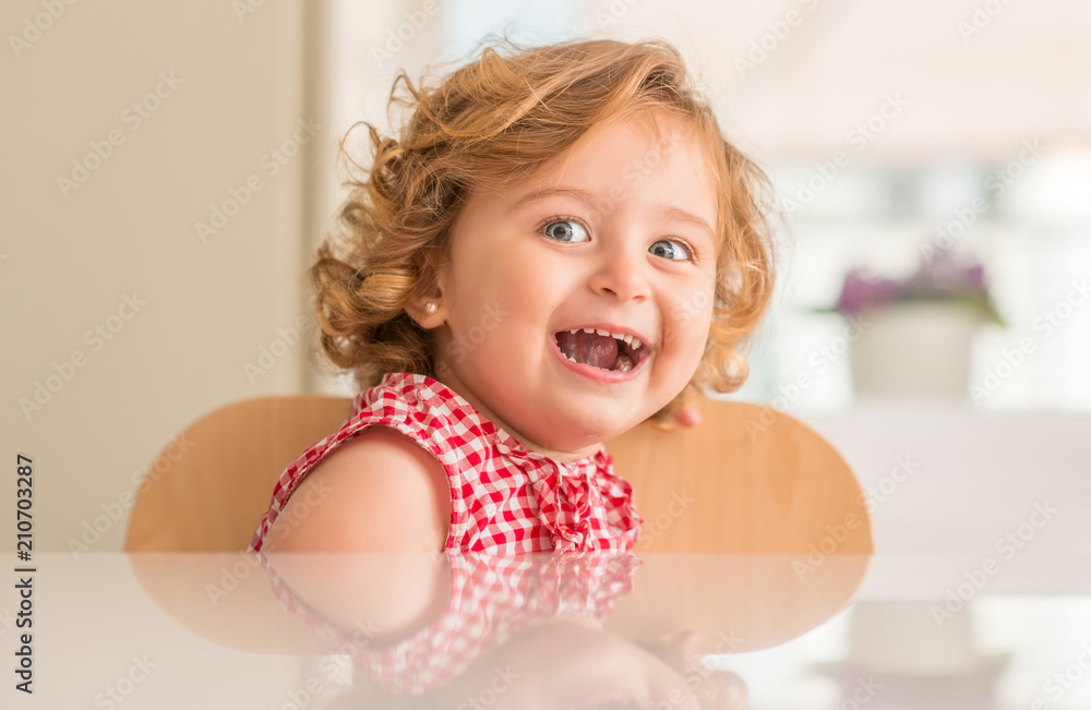 Obraz premium Beautiful blonde child with blue eyes sitting and looking side at home.