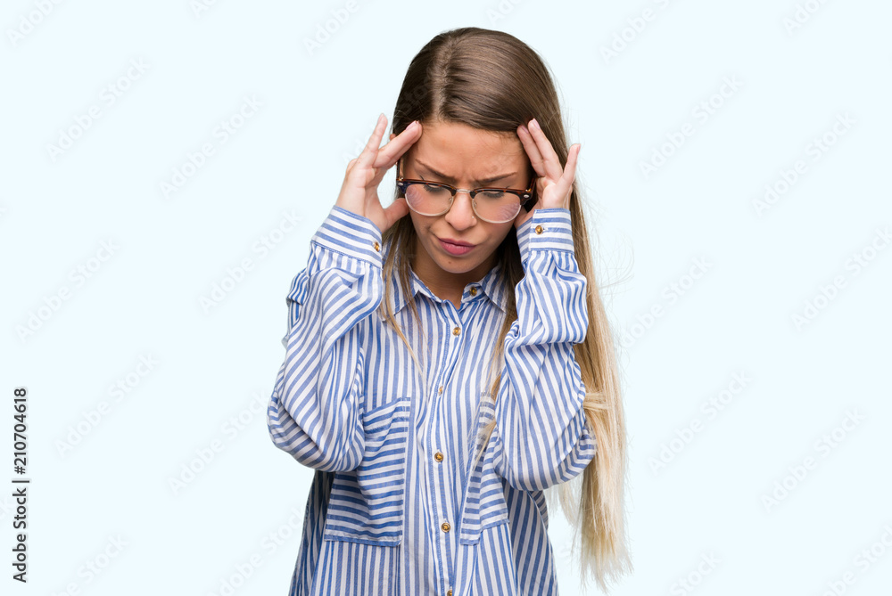 Beautiful young woman wearing elegant shirt and glasses with hand on head for pain in head because stress. Suffering migraine. Beautiful young woman wearing elegant shirt and glasses with hand on head for pain in head because stress. Suffering migraine.