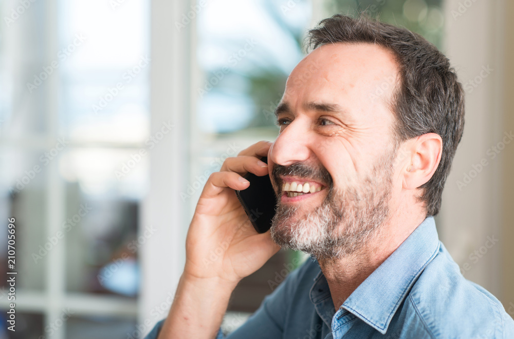 Middle age man using smartphone with a happy face standing and smiling with a confident smile showing teeth Middle age man using smartphone with a happy face standing and smiling with a confident smile showing teeth