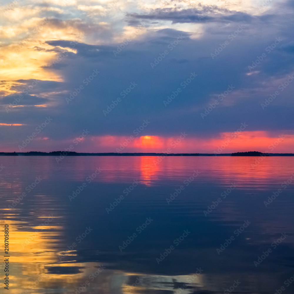 Red sunset and clouds reflected in calm water.