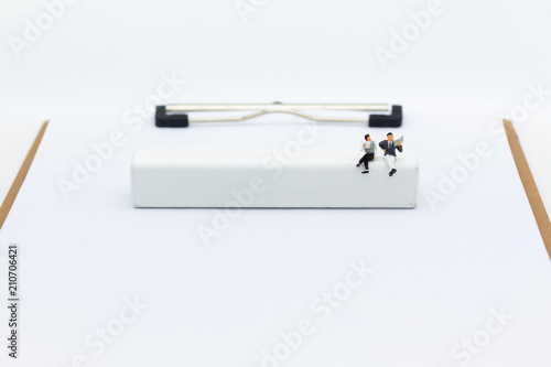 Miniature businessman sitting on white block, it can write for various occasions. Image use for business background concept.