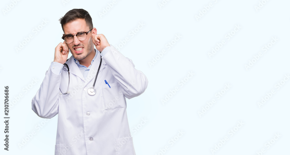 Handsome young doctor man covering ears with fingers with annoyed expression for the noise of loud music. Deaf concept. Handsome young doctor man covering ears with fingers with annoyed expression for the noise of loud music. Deaf concept.