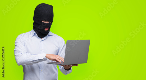 Business hacker man holding a computer laptop with a confident expression on smart face thinking serious