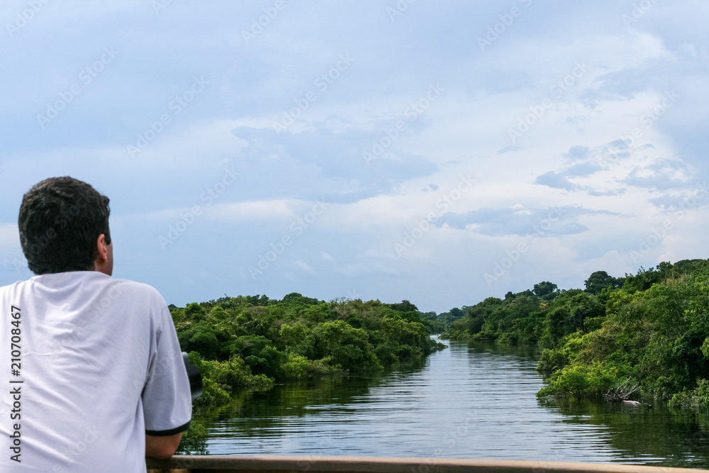 Amazonas, Brazil. A tourist contemplating the beautiful view of the Negro River during the flood season with the Amazon rainforest in the background.