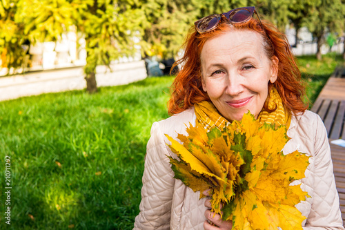 55 year old woman in autumn park with colored leaves