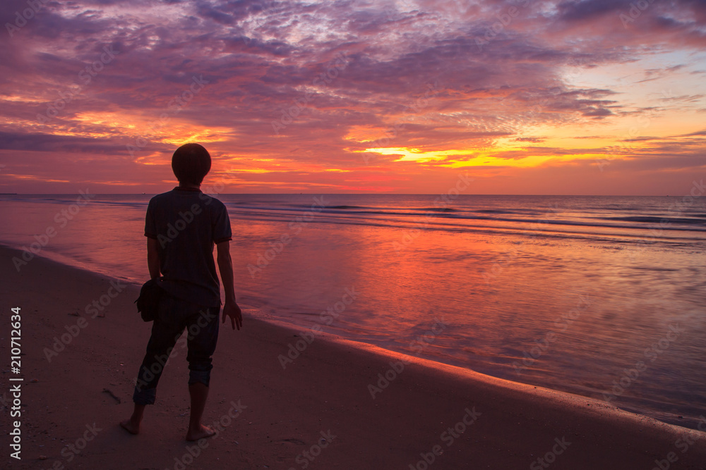 undefined traveler standing at the beach in sunrise time / Lonely man