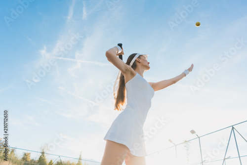 Woman serving the ball for a game of tennis on court © Kzenon