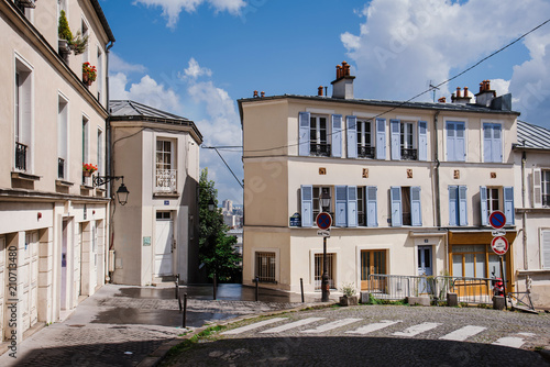 Fototapeta Naklejka Na Ścianę i Meble -  Paris, France - August 10, 2017. Cobbled street in Montmartre with old houses of traditional architecture, authentic parisian architectural complex. Narrow french cobblestone street with no people.