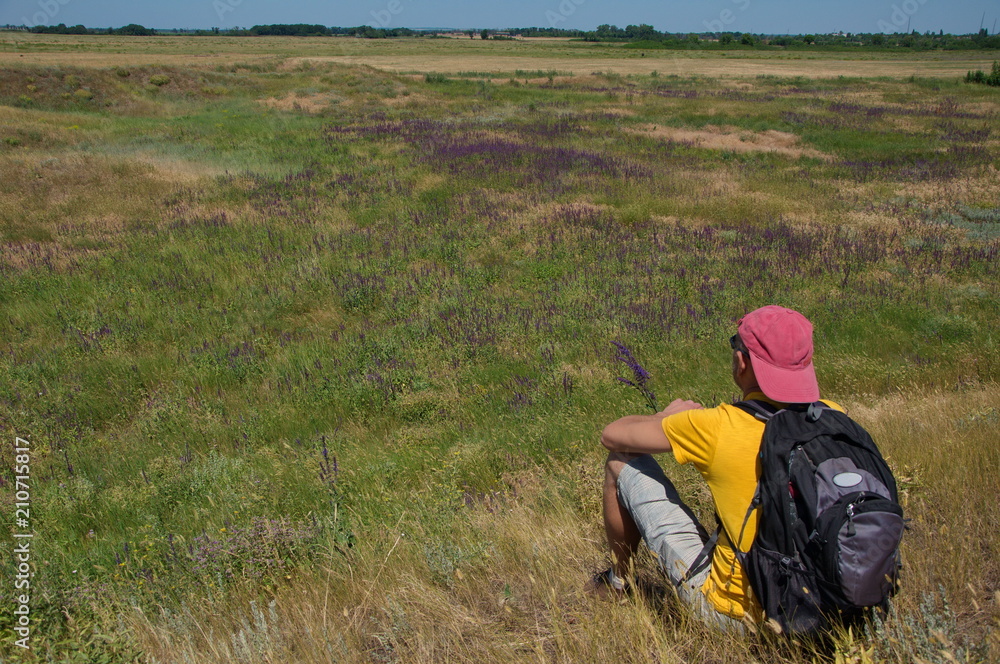 Man with a backpack resting on a meadow. Man with a backpack resting on a meadow.