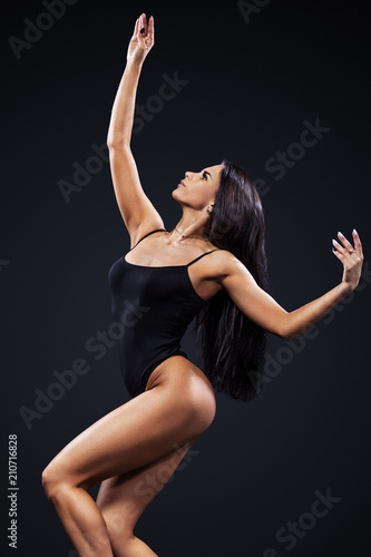 Beautiful young and fit ballet dancer jumping on a black background. Dance and sport concept. © Mike Orlov