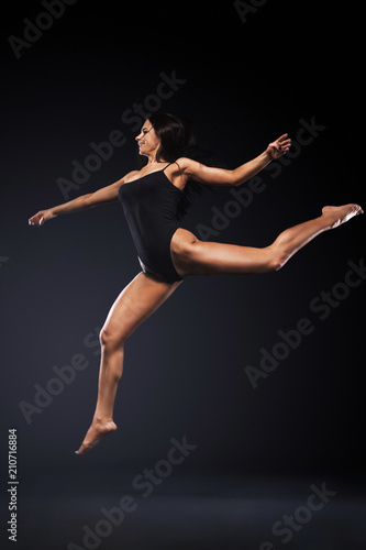 Beautiful young and fit ballet dancer jumping on a black background. Dance and sport concept. © Mike Orlov