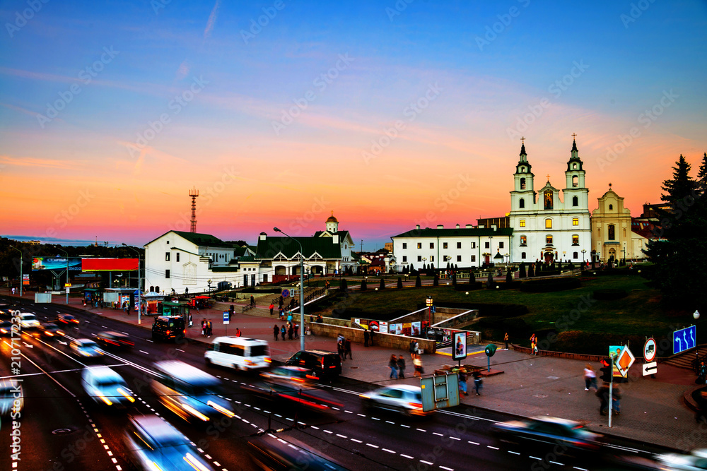 Obraz premium Aerial view of Minsk Cathedral with people and car traffic. Car trail lights and sunset sky.