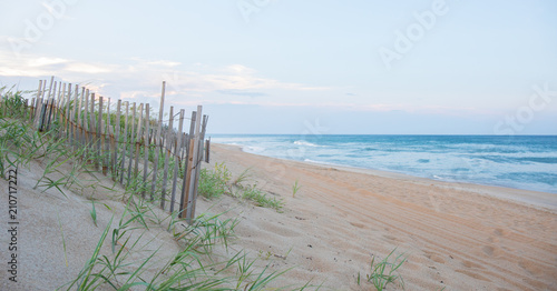 A sand dune fence at dusk with the ocean in the background.