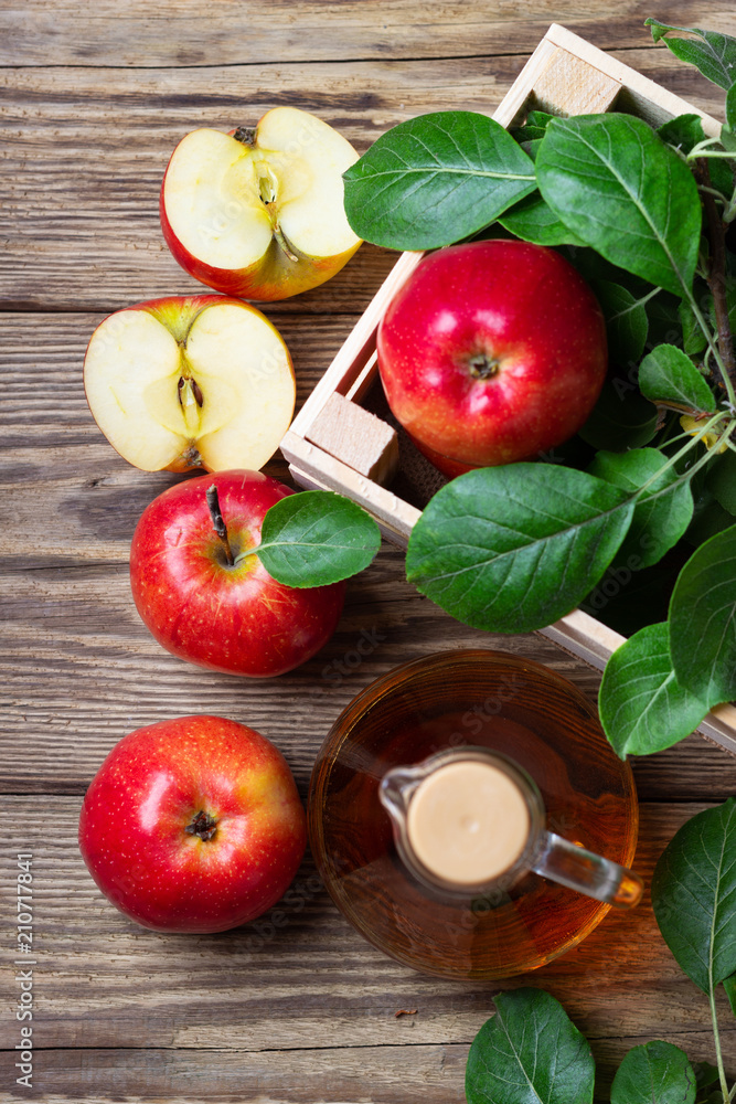 Apple cider vinegar and fresh red apple on a wooden background Apple cider vinegar and fresh red apple on a wooden background