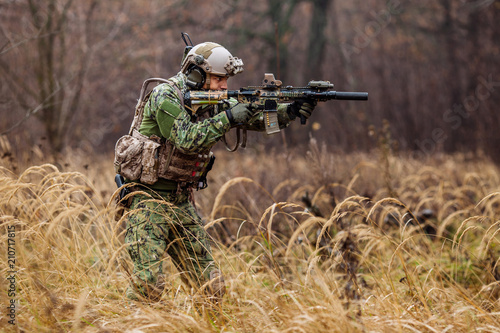 soldier with rifle in full gear. Military man on the background of nature. © kaninstudio