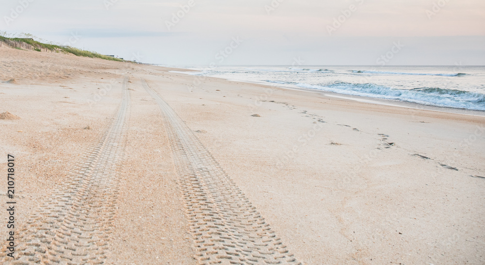 Tire tread marks in the sand leading off into the distance on the beach. Tire tread marks in the sand leading off into the distance on the beach.