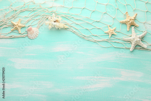 Different seashells with fishing net on mint wooden table