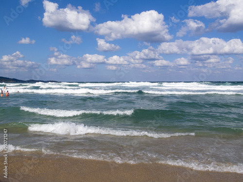 Waves meet a sandy Black Sea beach, bathing people in the water distance