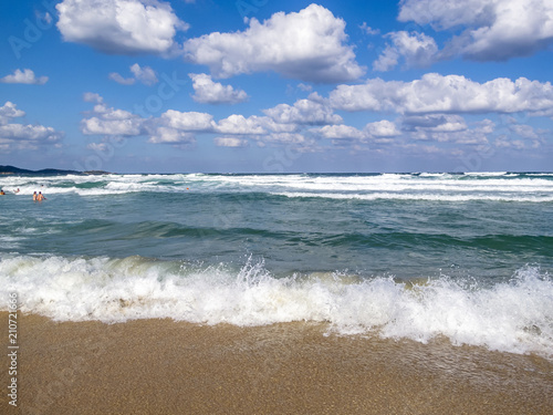 Wave meets a sandy Black Sea beach  bathing people in the water distance