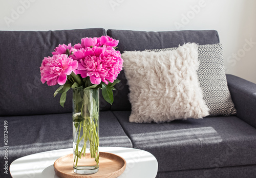 Peonies in the vase standing on the coffee table near the sofa