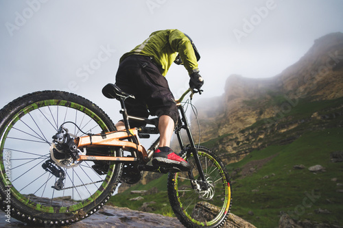 Extreme mountain bike sports athlete man in helmet riding outdoors against a background of rocks. Lifestyle. Trial