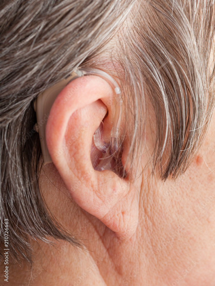 Closeup senior woman using hearing aid Closeup senior woman using hearing aid