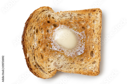 A single slice of whole wheat toast with a knob of melting butter isolated on white from above. photo