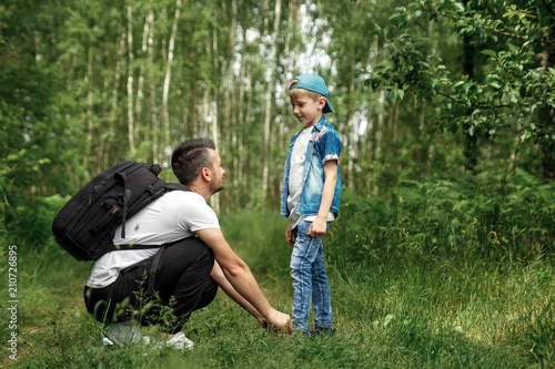 фотографія A man with a backpack, a father and his son on a hike, walking during walks in the woods