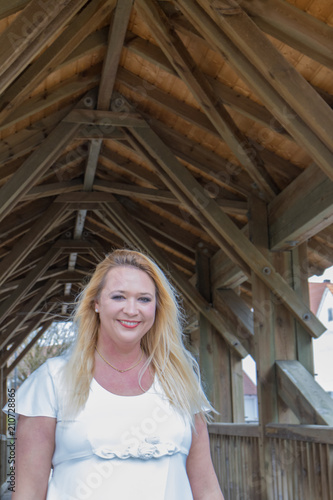 Blonde Frau in weißem Kleid unter Holzbrücke