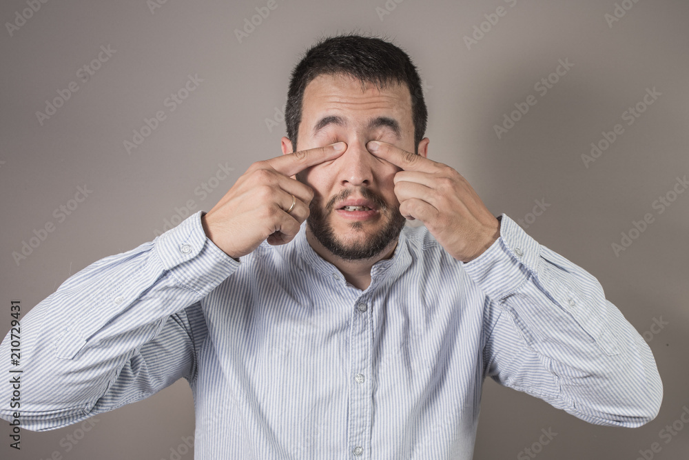 man scratching his eyes with the glasses removed man scratching his eyes with the glasses removed