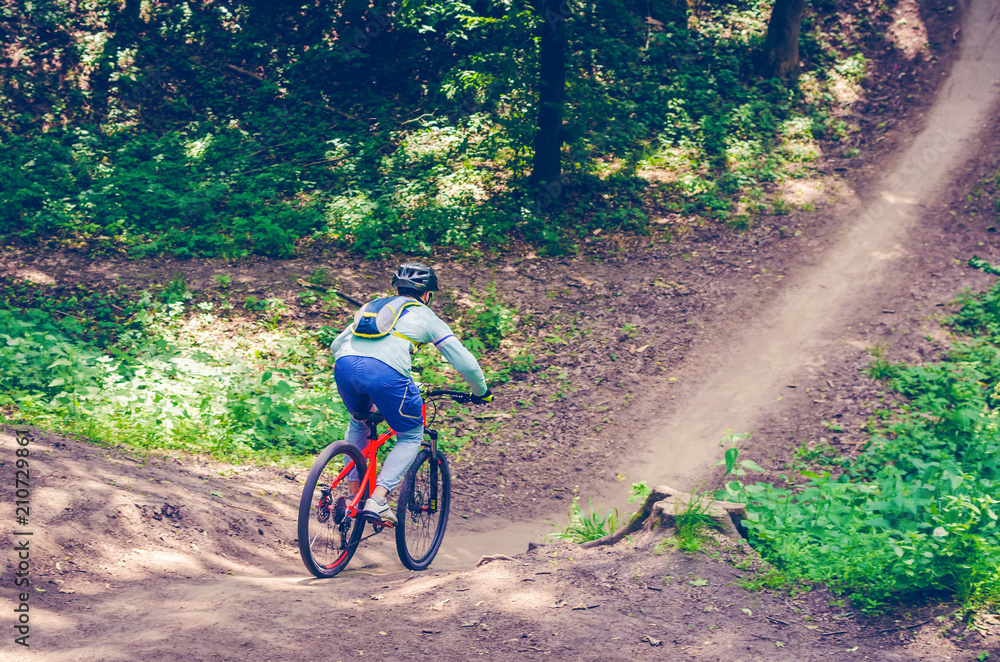 A cyclist in a helmet descends from the mountain on an orange bicycle A cyclist in a helmet descends from the mountain on an orange bicycle
