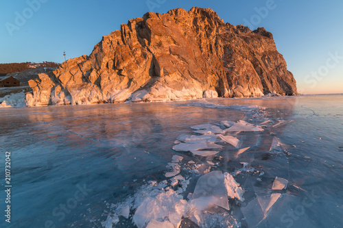 Lake Baikal in winter day. Cracks on the smooth surface of the ice near the cliffs of Olkhon Island