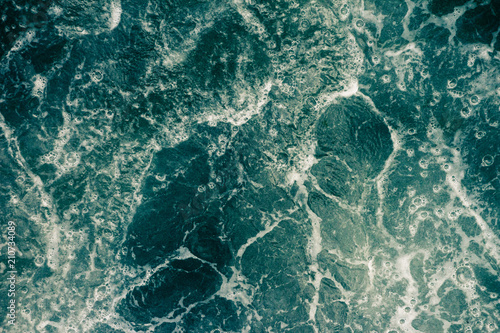 The surface of the sea with waves, foam and bubbles, green abstract background