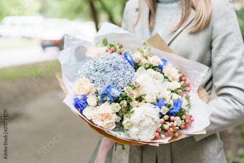 Young girl holding a beautiful spring bouquet. flower arrangement with hydrangea and peonies. Color light blue. The concept of a flower shop, a small family business
