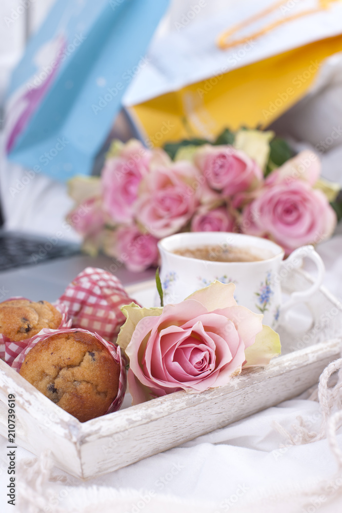 a white bed, packages with gifts, fresh coffee, breakfast cakes and a bouquet of pink roses. Good morning Vintage photo. copy space. a white bed, packages with gifts, fresh coffee, breakfast cakes and a bouquet of pink roses. Good morning Vintage photo. copy space.