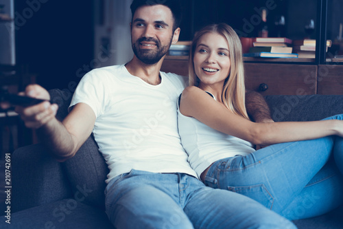 Smiling young couple relaxing and watching TV at home.