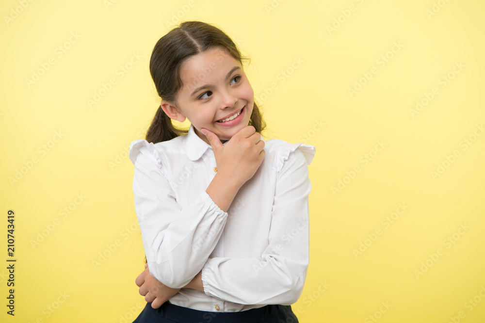 Happy child thinking on yellow background. Little daydreamer girl with cute smile. Lost in thoughts. Your dreams can send you far away. Adorable and smart, copy space Happy child thinking on yellow background. Little daydreamer girl with cute smile. Lost in thoughts. Your dreams can send you far away. Adorable and smart, copy space