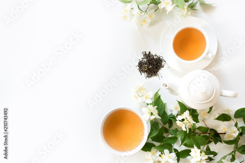 Green jasmin tea and jasmine flowers, cup of green tea on white. Top view. Teatime.