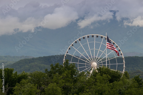 American flag with ferris wheel and mountains in background