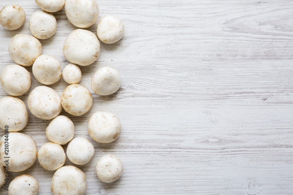 Champignon mushrooms on a white wooden table, top view. From above. Copy space. Champignon mushrooms on a white wooden table, top view. From above. Copy space.