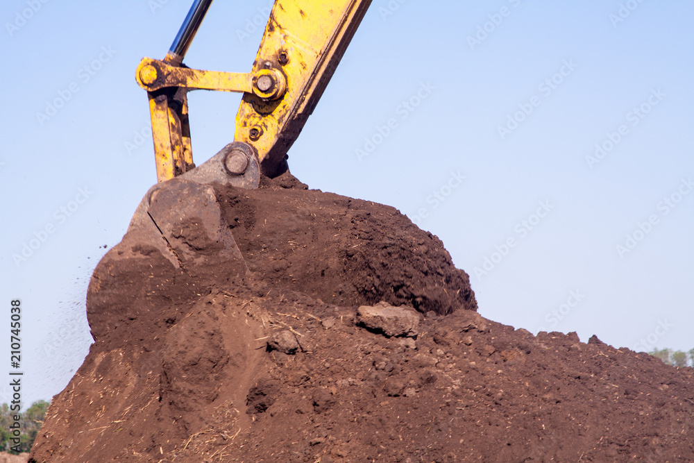 A large iron excavator bucket collects and pours sand rubble and stones in a quarry at the construction site of road facilities A large iron excavator bucket collects and pours sand rubble and stones in a quarry at the construction site of road facilities