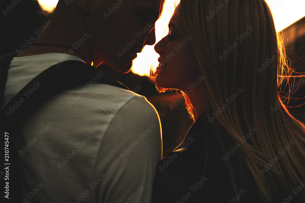 Adorable couple standing together at sunset - obrazy, fototapety, plakaty 