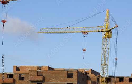 tower crane against the blue sky, the process of building a multi-storey building