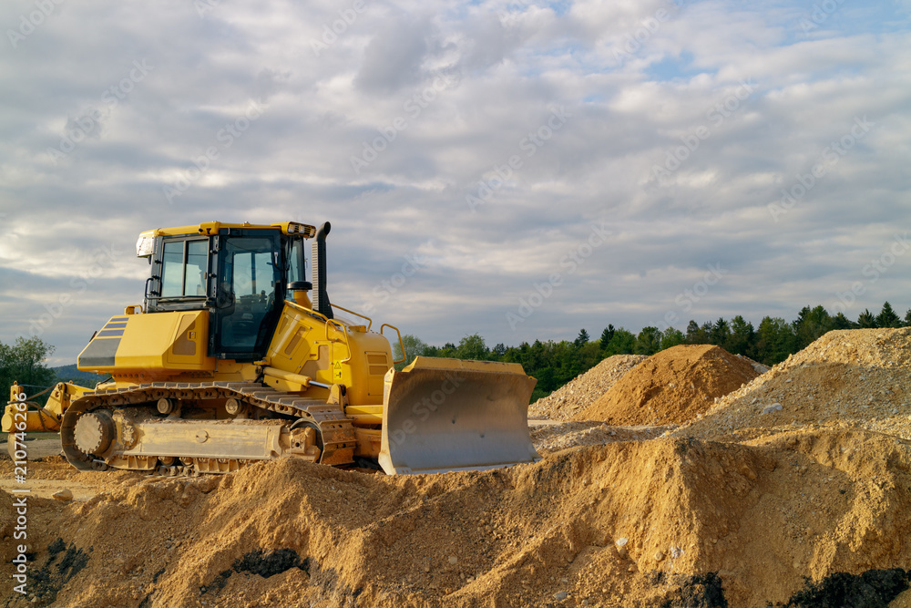 Obraz premium Bulldozer preparing terrain for building a road in the sunset.