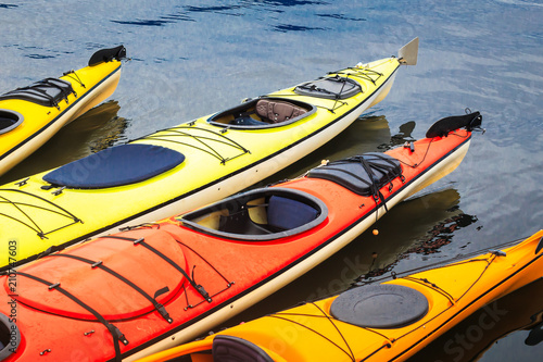 Colorful orange and yellow kayaks floating in the blue water photo