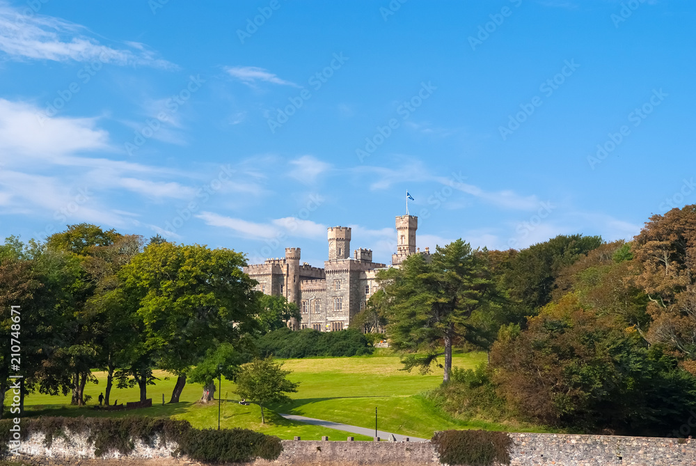 Lews Castle on estate landscape in Stornoway, United Kingdom. Castle with green grounds on blue sky. Victorian style architecture and design. Landmark and attraction. Summer vacation and wanderlust